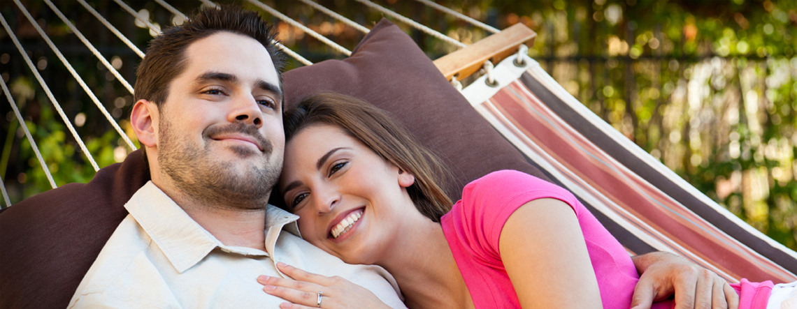 A smiling couple relaxing in a garden hammock